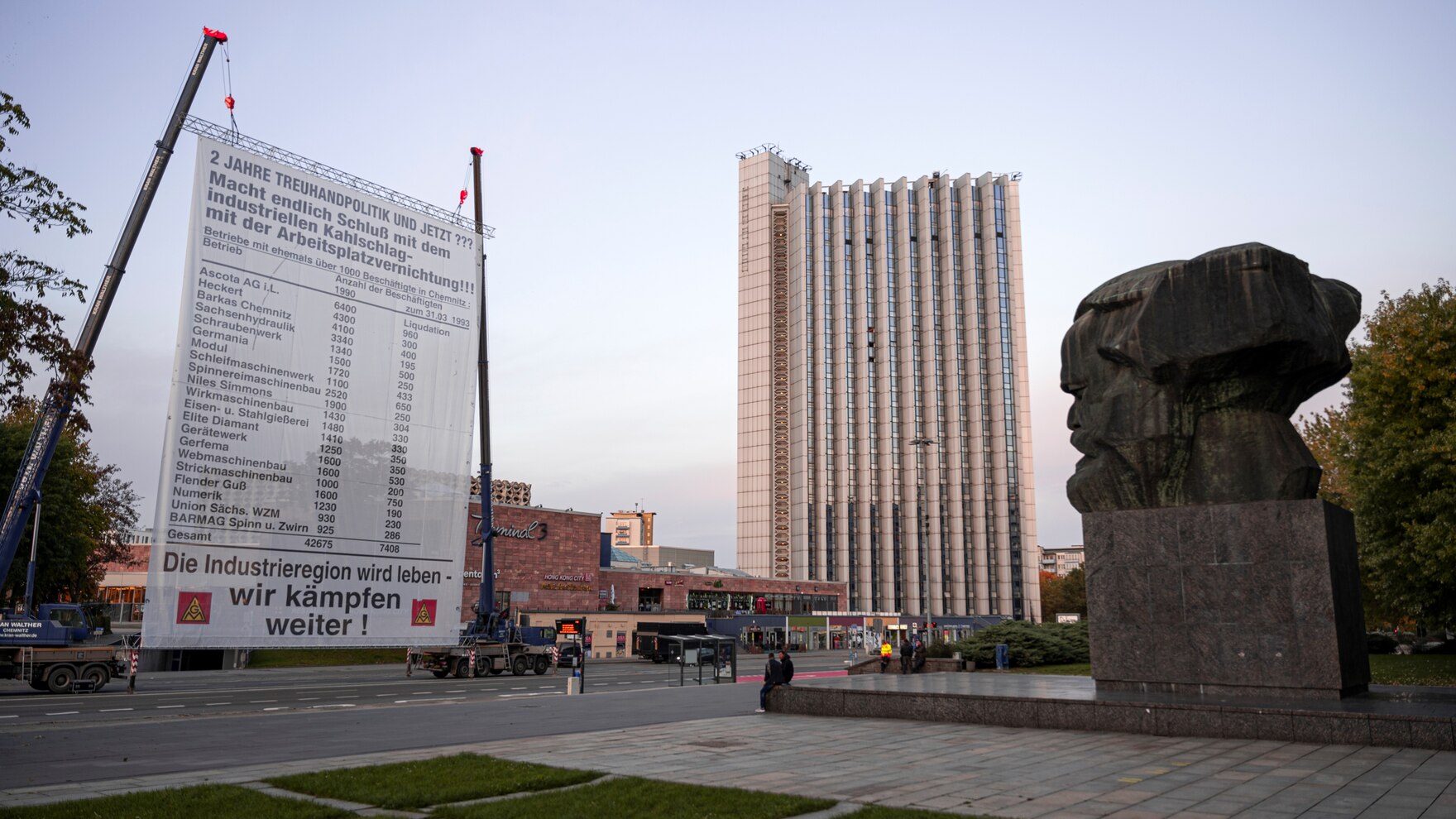 Ein großes Plakat an einem Kran befestigt, befindet sich vor dem Karl Marx Monument in Chemnitz.